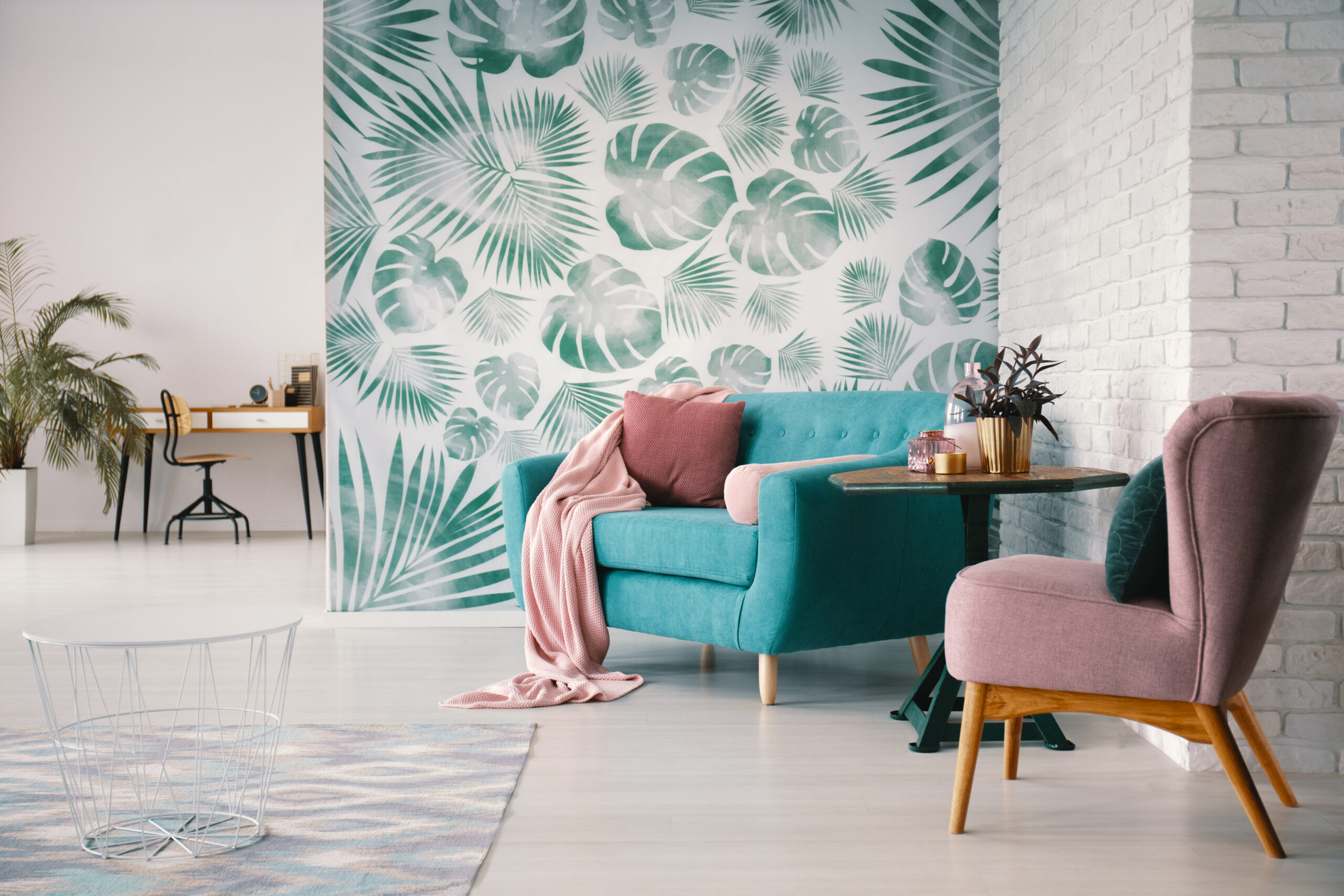 Chair and turquoise sofa in green living room interior with leav
